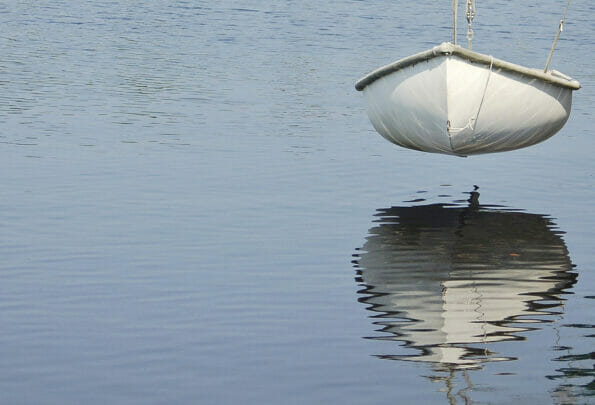 Reflection of a small dinghy suspended above water in the lake