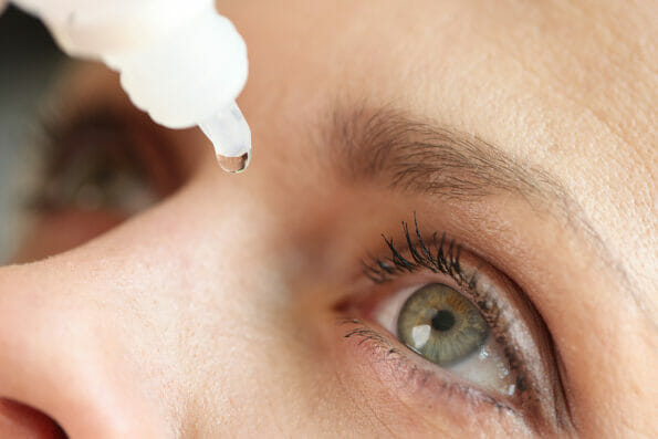 Caucasian woman using medical drops and dripping eye close up. Dry eyes syndrome, eye diseases and medical treatment concept.