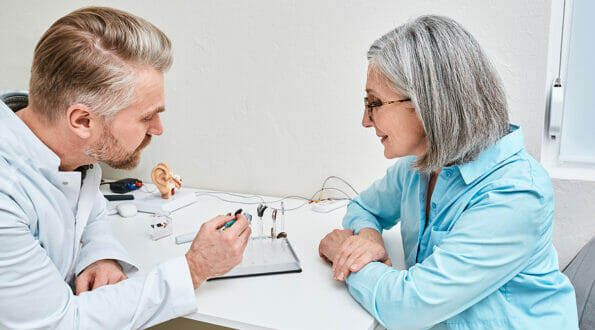 Hearing aids and solutions. Audiologist offers BTE hearing aids to woman patient with hearing problems for treatment her deafness