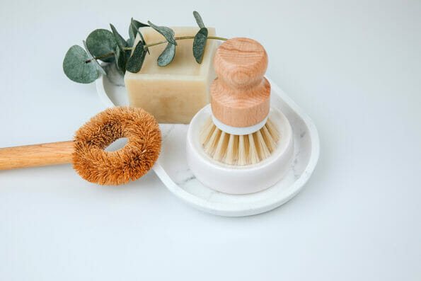 Set of eco friendly products. Washing brush and natural soap on a white marble tray with eucalyptus sprigs. Top view