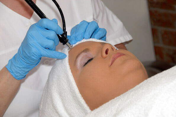 Laser skincare treatment Laser hair removal being preformed on forehead of woman wrapped in a towel.