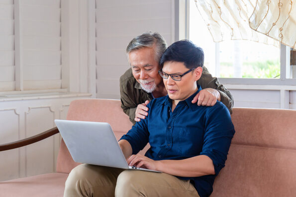 Senior Asian father and middle aged son in living room, Father ans son father using laptop together, Family and Father's day concepts